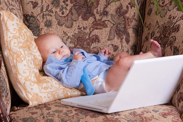 Serious businessman baby sits with the computer on sofa — Stock Photo, Image