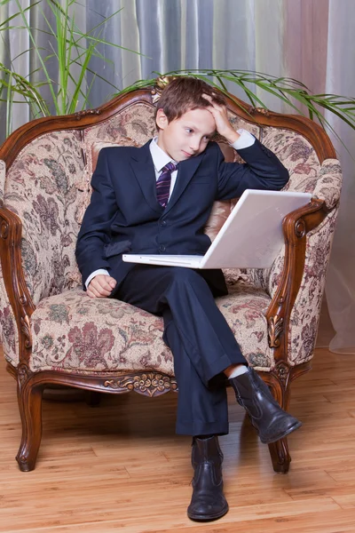 Worried young boy dressed in business suit working on computer — Stock Photo, Image