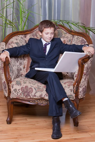 Young smiling boy dressed in business suite looking at white not — Stock Photo, Image