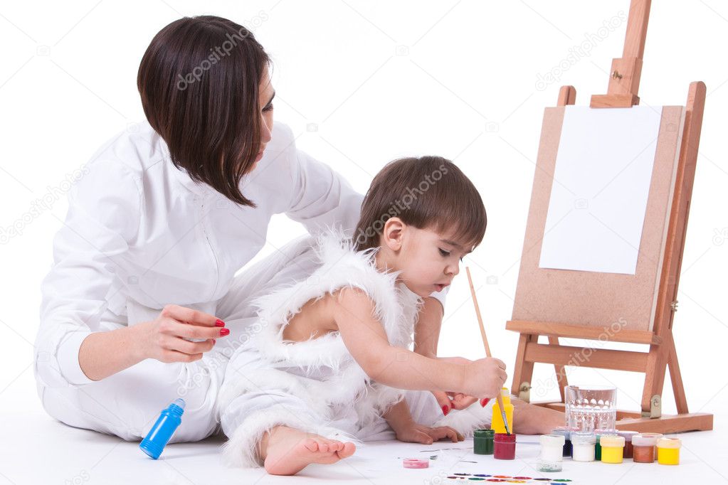 Happy mom and son dressed in white painting near easel
