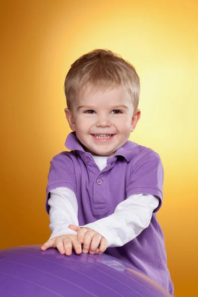 Menino feliz llaughs perto de grande bola violeta — Fotografia de Stock