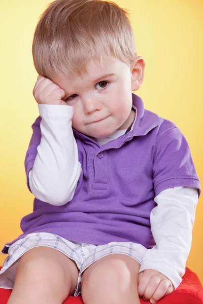 Sad cute little boy holding hand near head — Stock Photo, Image