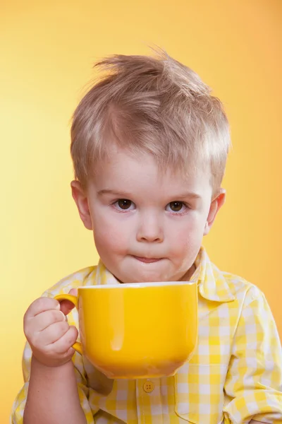 Funny little boy drink from big yellow cup — Stock Photo, Image