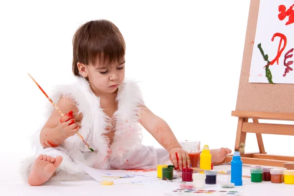 Симпатичный сидящий ребенок в белой живописи с кистью возле кисти — стоковое фото