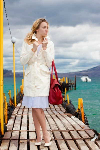 Nő, fehér, piros táska, séta a fából készült tengeri footbridge — Stock Fotó