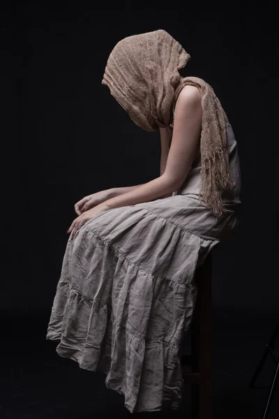 Conceptual portrait of sad woman in scarf sitting with hidden fa — Zdjęcie stockowe