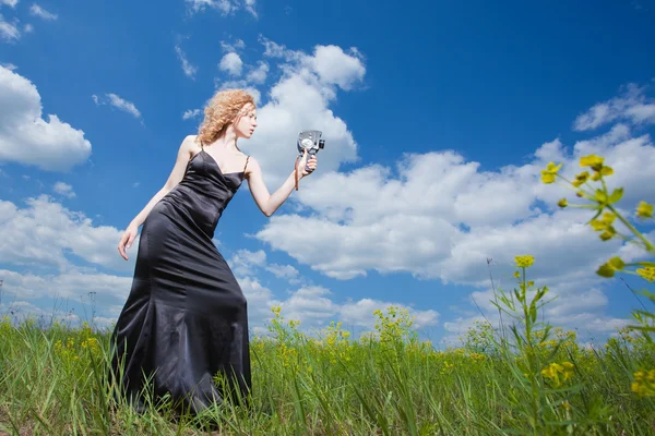 Mulher bonita pashionate no campo filmando com câmera velha — Fotografia de Stock