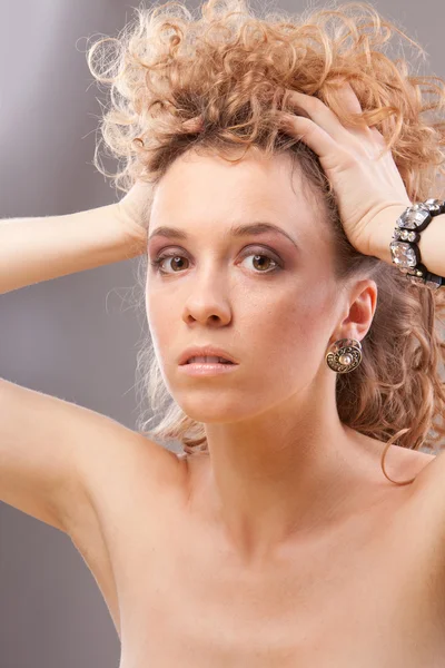 Beautiful young blonde curly woman holding head with hands — Stock Photo, Image