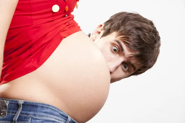 Meglepett ember kandikál ki a terhes hasa mögött Stock Kép
