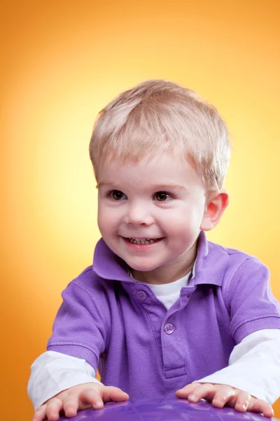 Gelukkig jongetje lacht in de buurt van violet bal — Stockfoto