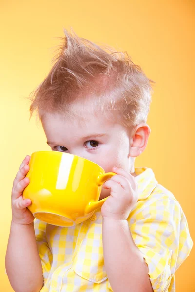 大きな黄色のカップから面白い小さな男の子の飲み物の肖像画 — ストック写真