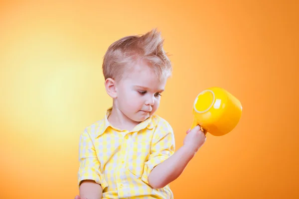 Смішний маленький хлопчик показує велику жовту порожню чашку — стокове фото