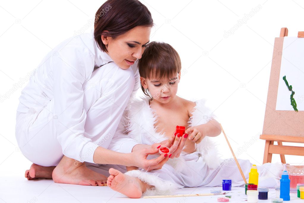 Mom and son dressed in white learning to paint near easel