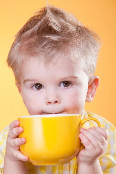 Смішний хлопчик п'є з жовтої чашки — стокове фото