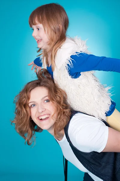 Smiling mother playing with daughter on her shoulders — Stock Photo, Image