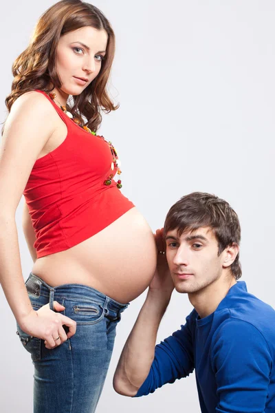 Člověk naslouchat břicho těhotné ženy — Stock fotografie