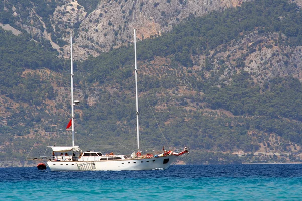 Яхта против горного турецкого побережья — стоковое фото