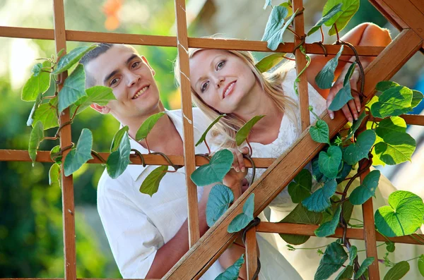 Young happy couple at wooden lattice — Stock Photo, Image