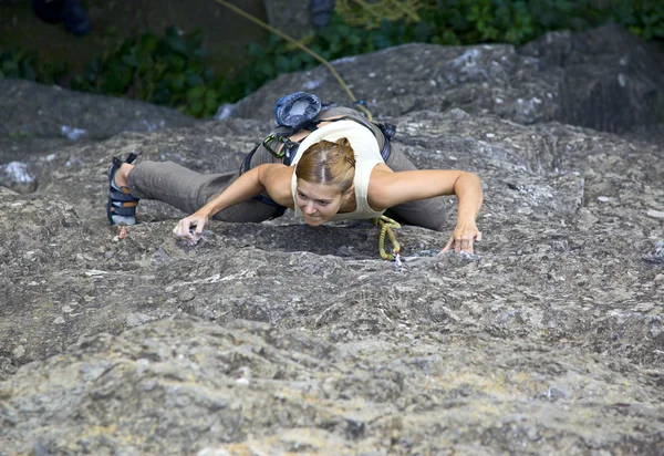 Женщина-скалолаз цепляется за скалу, пробиваясь наверх. — стоковое фото