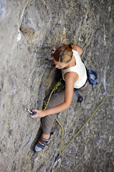 Arrampicante di roccia femminile aggrappata a una scogliera mentre combatte la sua strada fino — Foto Stock