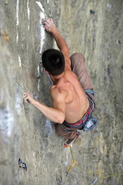 Masculino escalador de rocha se apega a uma rocha pendurada — Fotografia de Stock