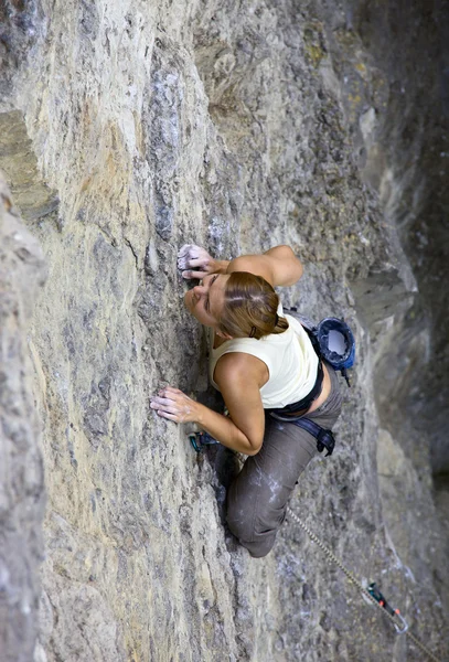 Mujer escaladora aferrada a un acantilado mientras lucha por ascender — Foto de Stock
