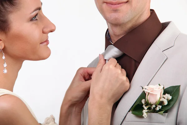 Noiva ajustando gravata do noivo no fundo branco — Fotografia de Stock