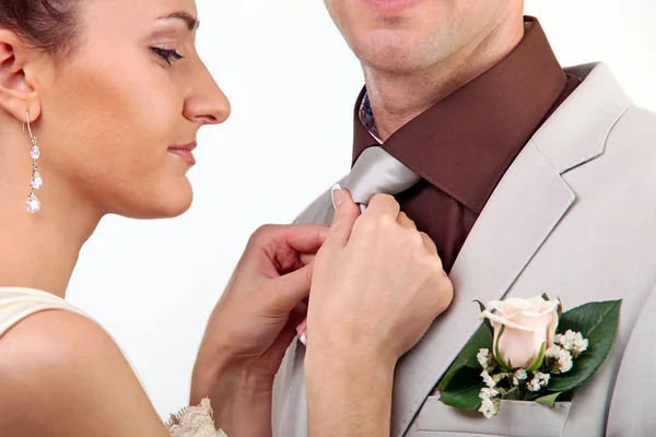 调整新郎的领带在白色背景上的新娘 — 图库照片