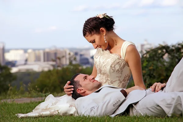 Casal de casamento feliz deitado na grama no parque — Fotografia de Stock