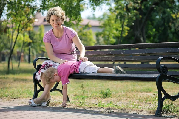 Feliz madre e hijo sentados en el banco en un parque de la ciudad —  Fotos de Stock