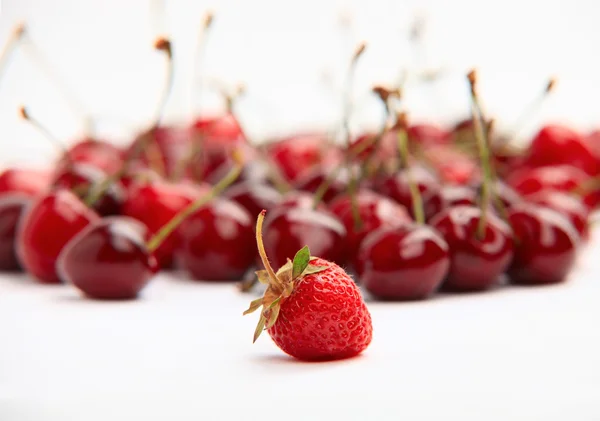 Single strawberry on background of cherries — Stock Photo, Image
