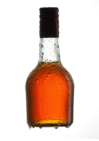 Botella de coñac con gotas de agua aisladas sobre fondo blanco —  Fotos de Stock