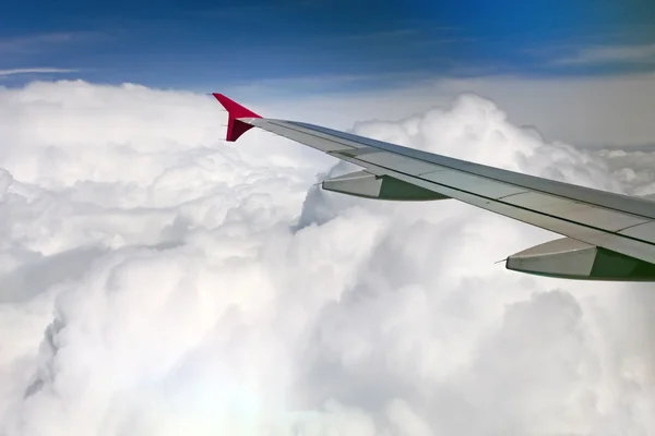 Vista da asa do avião a jato no fundo de nuvens grossas e céu azul — Fotografia de Stock