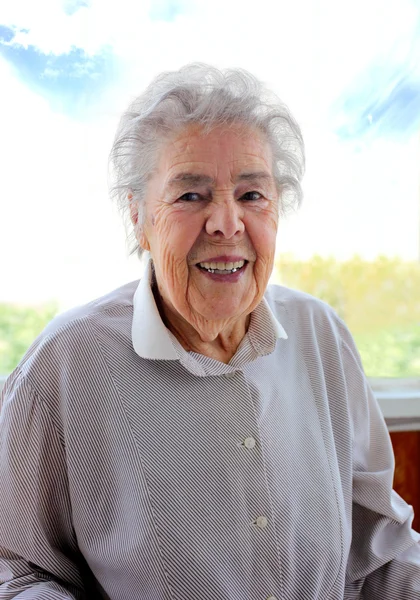 Senior mosolygó nő a háttérben az ablak portréja — Stock Fotó