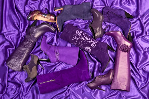 Chaussures et bottes violettes pour femmes placées sur du satin violet — Photo