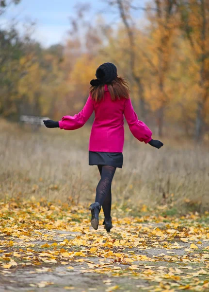 Женщина в розовом пальто бегает в парке — стоковое фото