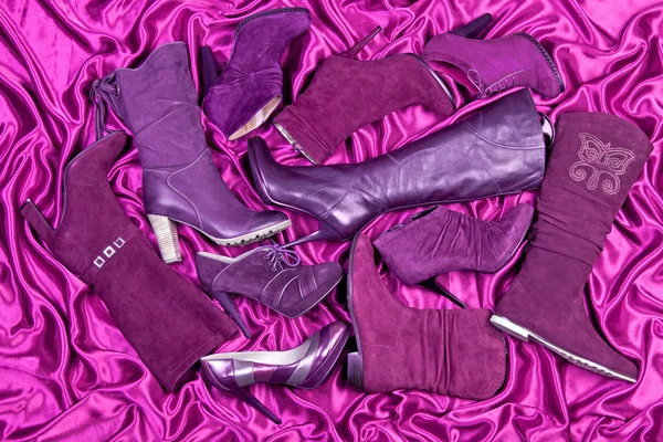 Scarpe e stivali viola femminili posizionati su raso viola — Foto Stock