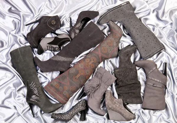 Zapatos y botas para mujer colocados en satén gris plateado —  Fotos de Stock