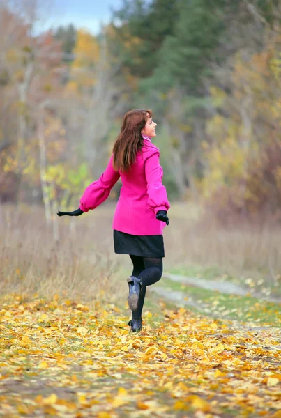 Woman in the pink coat running in the park — Stock Photo, Image