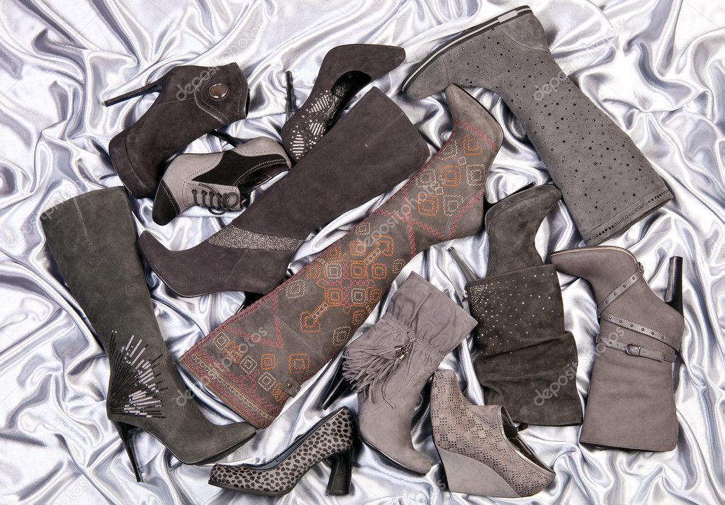 Female shoes and boots placed on silver-grey satin