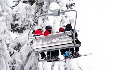 Skiers on a ski-lift. One skier waving his hand. clipart