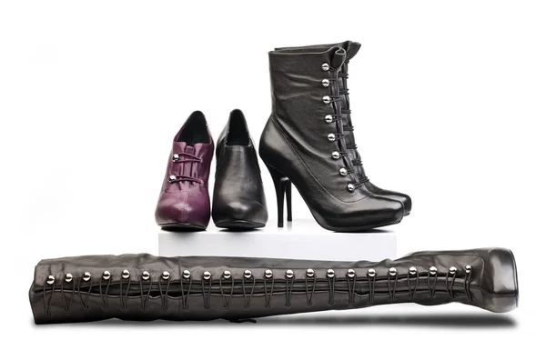 Bottes féminines à talons hauts sur fond blanc. Paire de bottes laquées noires, bottines violettes et bottines noires placées sur pied et bottines noires — Photo