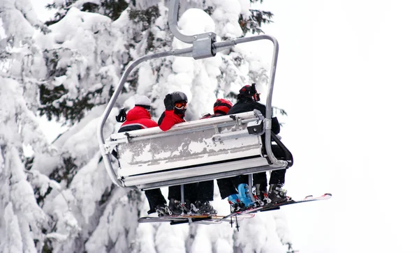 Skiërs op een ski-lift. 1 skieer zwaaien van zijn hand. — Stockfoto