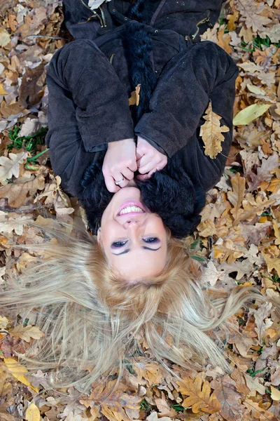 Mulher jovem bonita que se deita na folhagem de outono, vista de cima — Fotografia de Stock