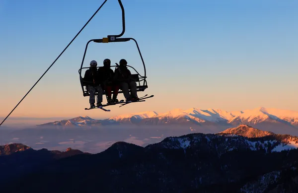 Chair ski lift with skiers over blue sky in the evening — Stock Photo, Image