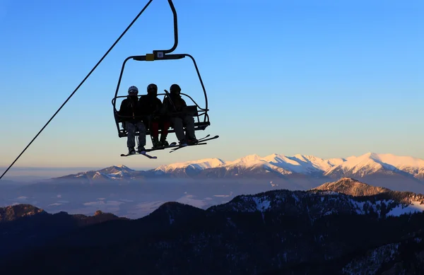 Silla telesilla con esquiadores sobre cielo azul y montañas —  Fotos de Stock