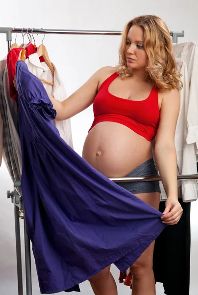 Belle jeune femme enceinte qui choisit quoi porter — Photo