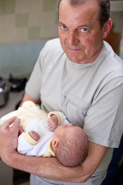 Großvater hält liebevoll seinen neugeborenen Enkel — Stockfoto