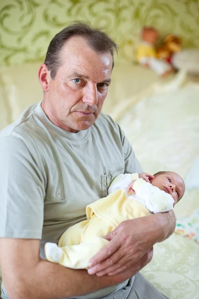 愛情を込めて彼の孫の新生児を保持している祖父 — ストック写真