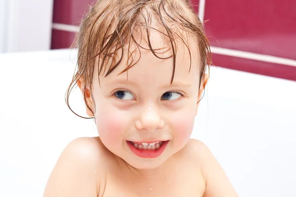 Linda chica de dos años de edad, mirando desde un baño y sonriendo —  Fotos de Stock